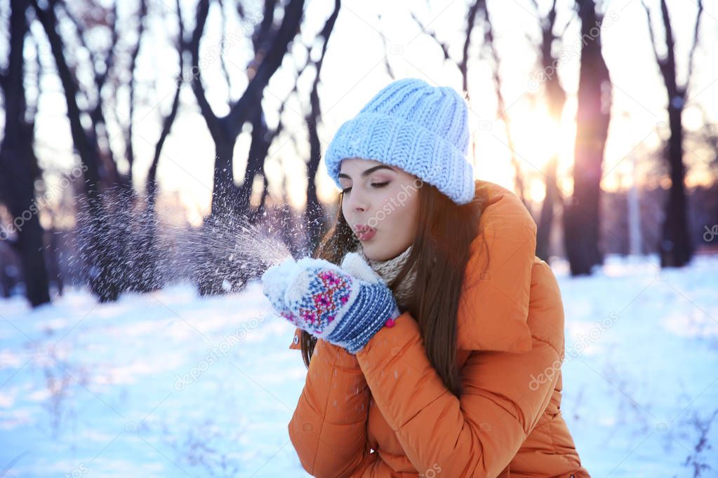 Beautiful young woman playing with snow 