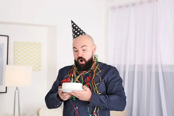 Hombre gordo divertido soplando vela en pastel de cumpleaños en la fiesta —  Fotos de Stock
