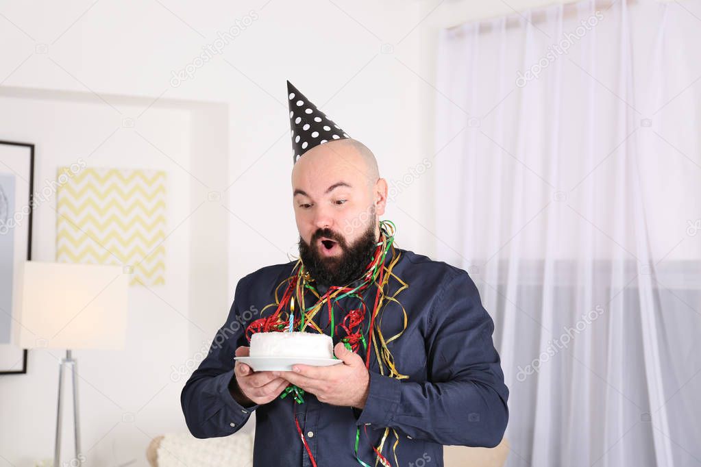 Funny fat man blowing out candle on birthday cake at party