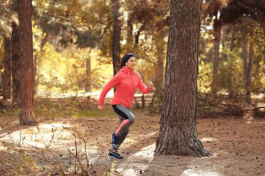 Genç bayan parkta koşuyor.