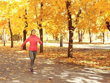 Genç bayan parkta koşuyor.