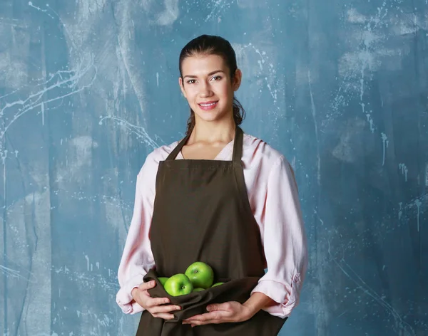 Mujer sosteniendo manzanas en delantal — Foto de Stock