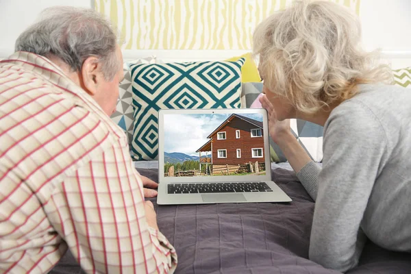 Online shopping concept. Senior couple looking for house on real estate market website