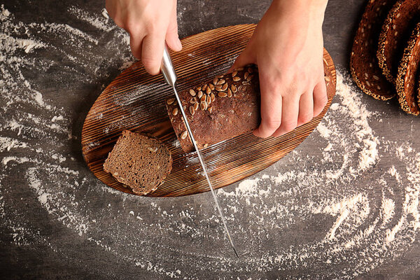 Female hands cutting rye bread
