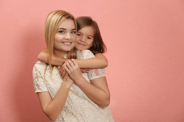 Schöne junge Frau und ihre Tochter auf farbigem Hintergrund. Muttertagskonzept — Stockfoto