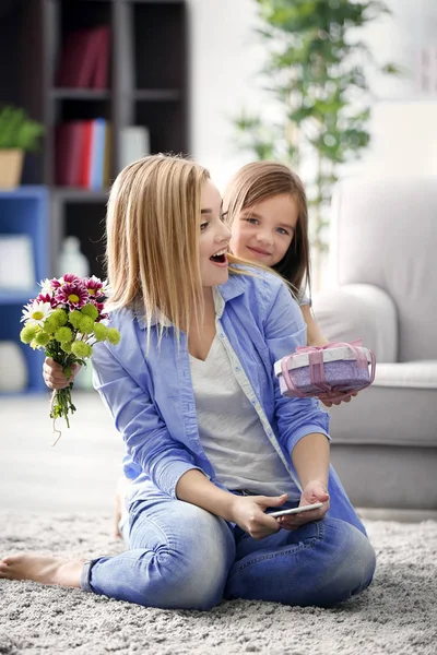 Liten flicka ger presentera hennes mor hemma. Mors dag koncept — Stockfoto