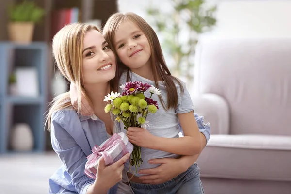 Vacker ung kvinna med närvarande och blombukett från hennes dotter. Mors dag koncept — Stockfoto