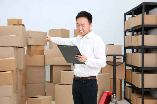 Mann mit Klemmbrett überprüft Aufträge im Lager eines Logistikunternehmens — Stockfoto