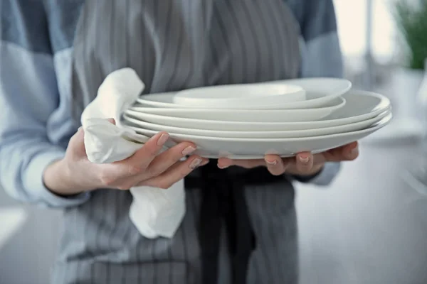 Женщина в фартуке с посудой — стоковое фото
