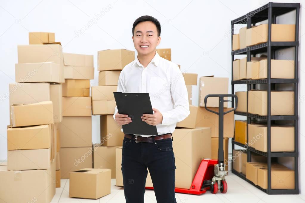 Handsome man with clipboard in logistics company warehouse