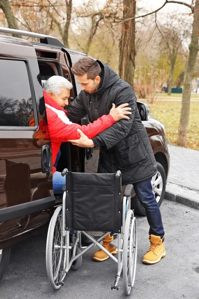 帮助老人坐在轮椅上的男人 — 图库照片