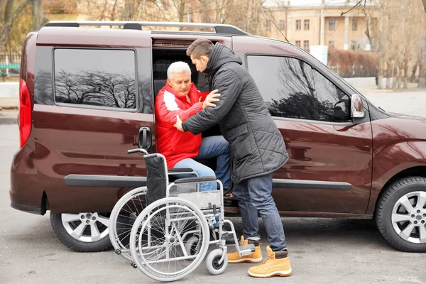 Hombre ayudando al hombre a sentarse en silla de ruedas —  Fotos de Stock