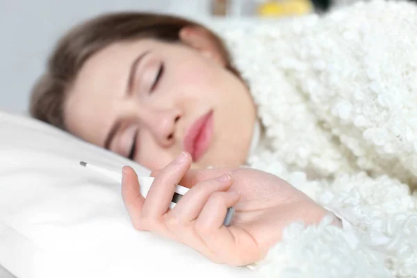 Jonge zieke vrouw met elektronische thermometer — Stockfoto