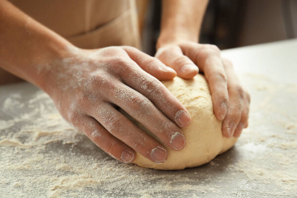 Male hands kneading dough 