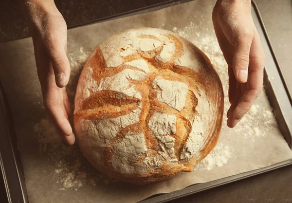 Mannelijke handen met vers gebakken brood — Stockfoto