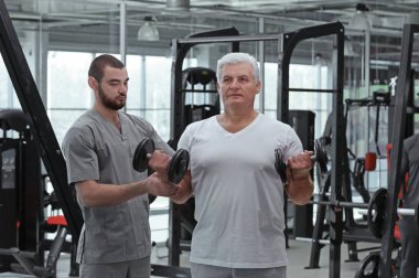 Rehabilitasyon kavramı. Olgun adam fizyoterapist gözetiminde egzersizleri yapıyor