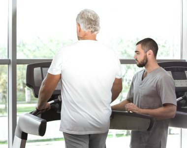 Rehabilitasyon kavramı. Olgun adam fizyoterapist gözetiminde egzersizleri yapıyor