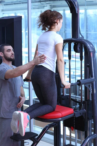 Концепция реабилитации. Молодая женщина делает упражнения под наблюдением физиотерапевта — стоковое фото