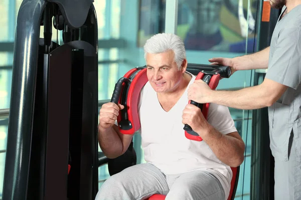 Conceito de reabilitação. Homem maduro fazendo exercícios sob supervisão fisioterapeuta — Fotografia de Stock
