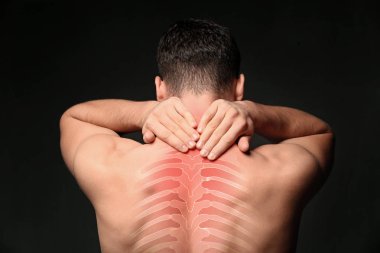 Young man suffering from neck pain on black background. Health care concept clipart
