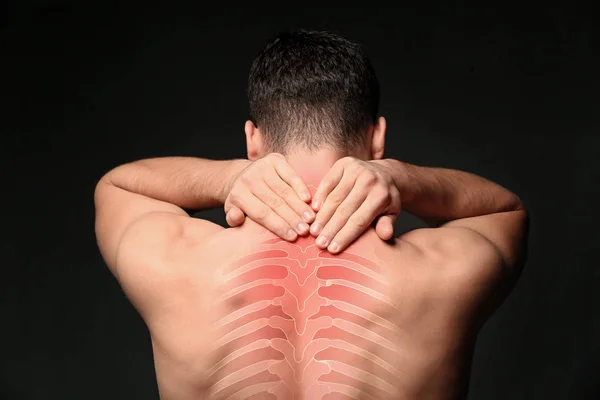 Young man suffering from neck pain on black background. Health care concept — Stock Photo, Image