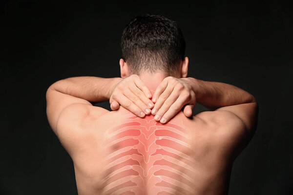 Young man suffering from neck pain on black background. Health care concept