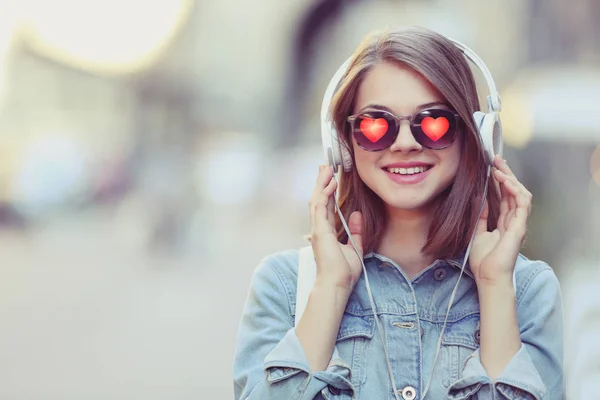 Giovane bella donna che indossa occhiali da sole con cuori su sfondo sfocato — Foto Stock