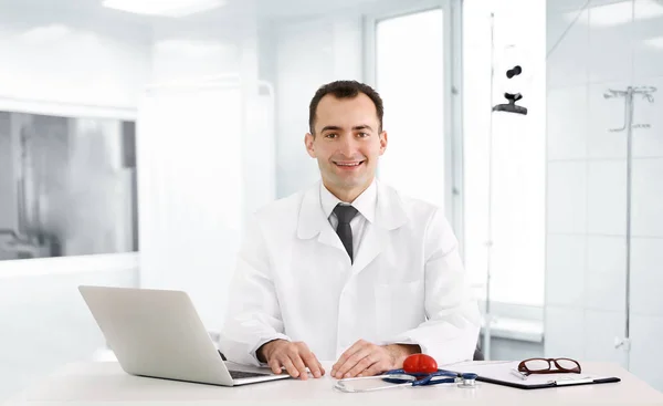 Médico sentado à mesa em consultório — Fotografia de Stock