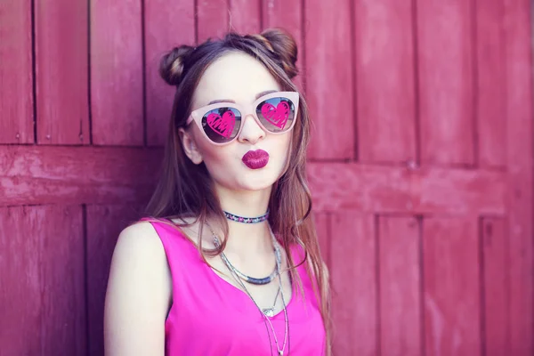 Beautiful teenager wearing sunglasses with hearts on wooden wall background — Stock Photo, Image