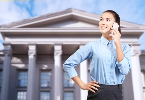 Law and justice concept. Young woman talking on phone against courthouse background — Stock Photo, Image