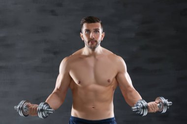 Sportif adam koyu arka plan üzerinde dumbbells ile yapıyor