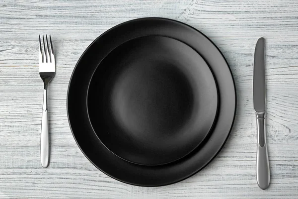 Пустая тарелка, вилка и нож на деревянном фоне — стоковое фото