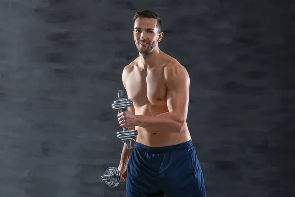 Sporty man doing exercises with dumbbells on dark background — Stock Photo, Image