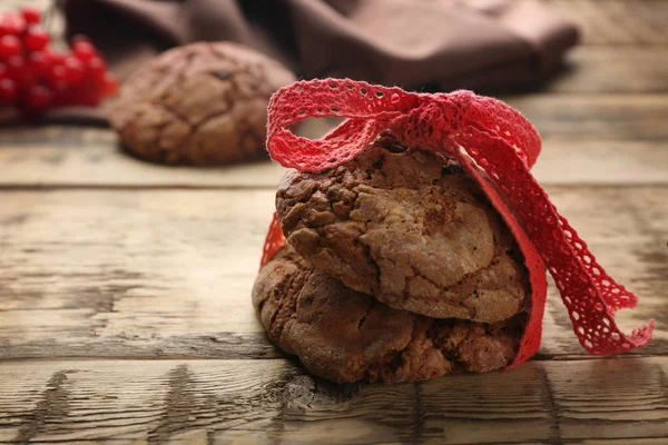 Deliciosos biscoitos de chocolate com fita em fundo de madeira — Fotografia de Stock