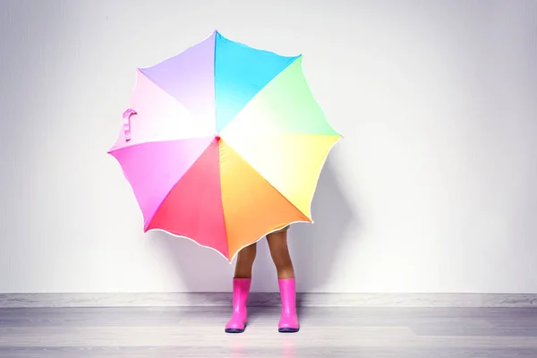 Menina afro-americana bonito com guarda-chuva em botas de borracha contra a parede leve. Conceito de moda — Fotografia de Stock