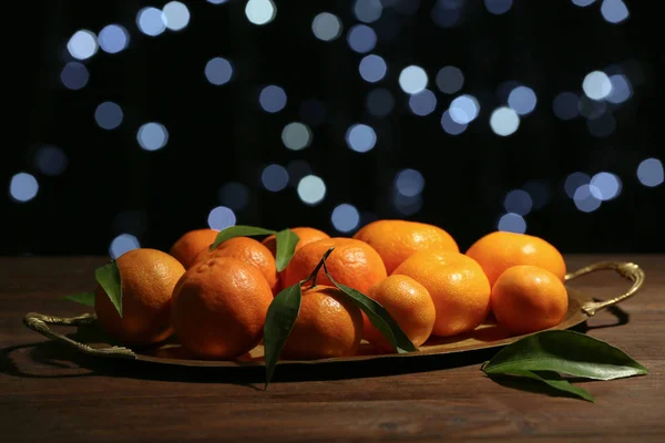 Tangerine på bricka mot oskärpa lampor — Stockfoto