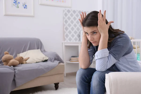 Mujer joven deprimida sentada en sillón en casa — Foto de Stock