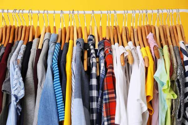 Hangers with colorful clothes on rack, closeup