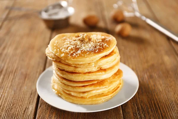Delicious pancakes with nuts on wooden table — Stock Photo, Image