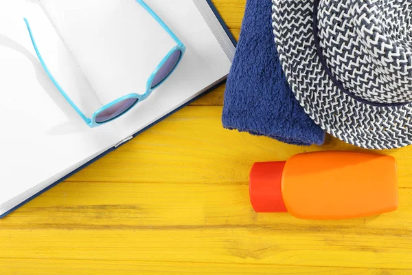 Vacation concept. Book and beach gear on yellow wooden table — Stock Photo, Image