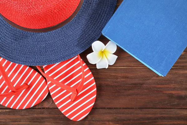 Vacation concept. Book, hat and flip-flops on wooden table — Stock Photo, Image