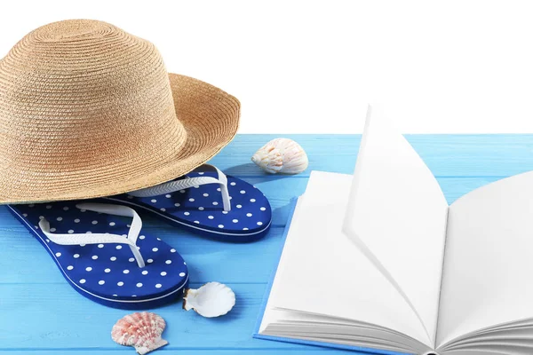 Концепция отпуска. Книга, шлепанцы и шляпа на синем деревянном столе — стоковое фото