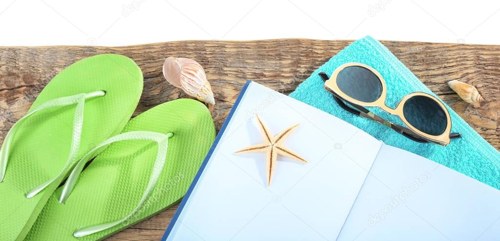 Vacation concept. Opened book, flip-flops, sunglasses and towel on wooden table