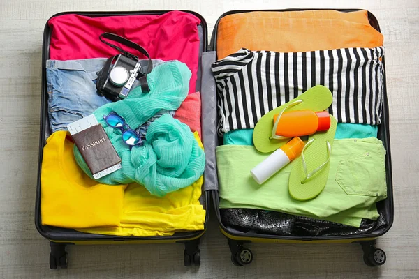 Открытый чемодан с путешественником на деревянном фоне — стоковое фото