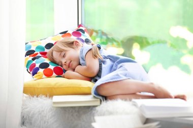 Pencere kenarında uyuyan sevimli küçük kız