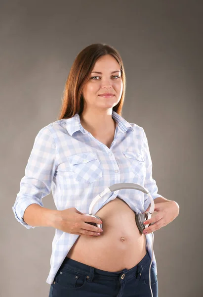 Mulher grávida segurando fones de ouvido — Fotografia de Stock