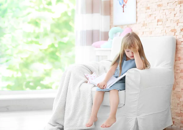 可爱的小女孩坐在扶手椅里拿着本书 — 图库照片