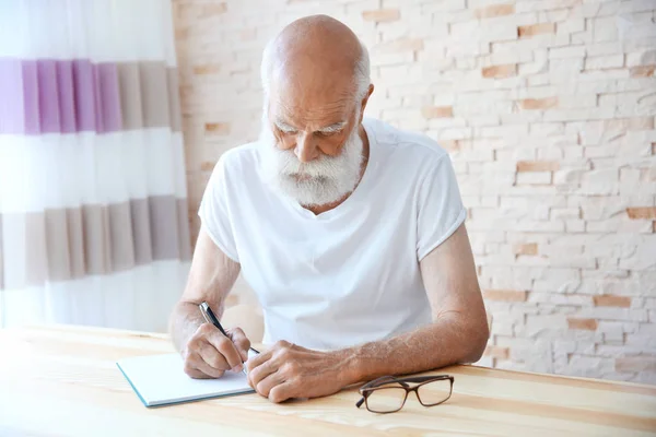 Старший человек с ручкой и блокнотом — стоковое фото