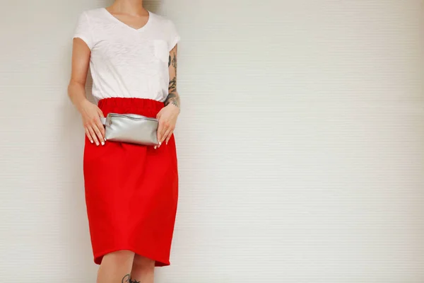 Stylish young woman with silver clutch on light background