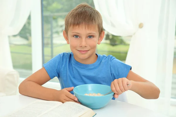 牛乳とコーンフレークのボウルで テーブルに座っている少年 — ストック写真